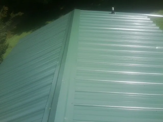 New green metal panels meeting at the ridge of a roof — Flat Roof Repair work by our crew in Dawson