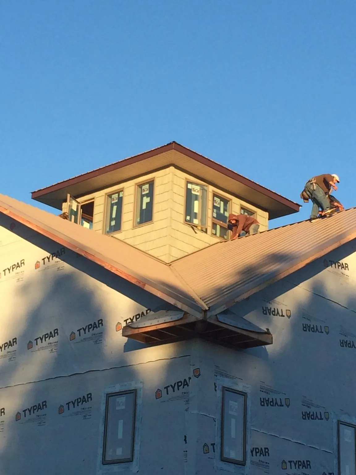 Roofers working around a rooftop cupola on a new metal roof at sunset — Roof Waterproofing in Dawson by Roofing Brothers